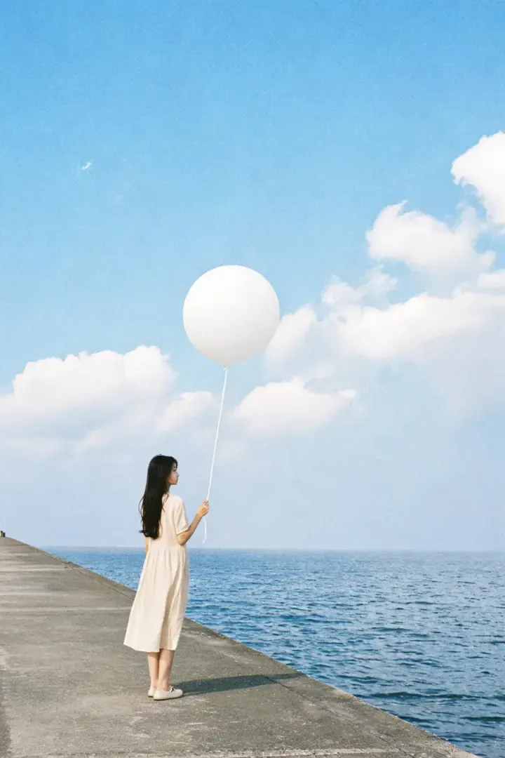 海边人物与白色气球的写实摄影作品